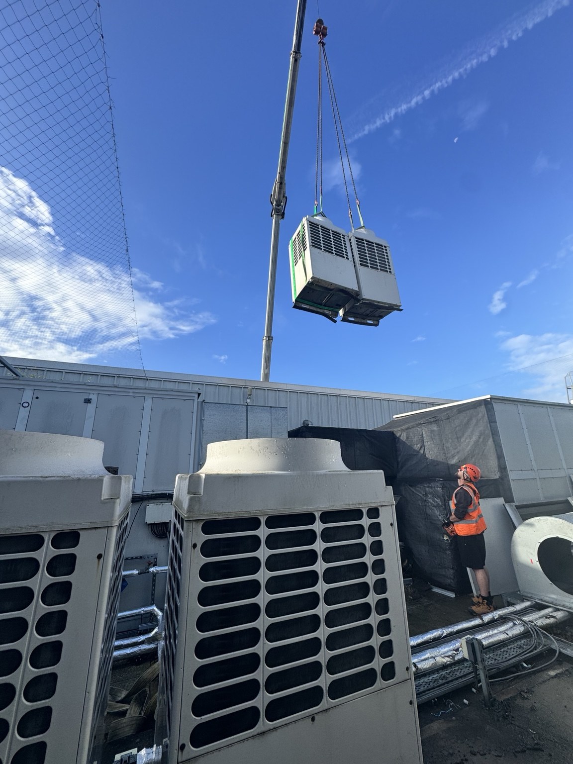 Crane lifting replacement HVAC plant onto a commercial rooftop